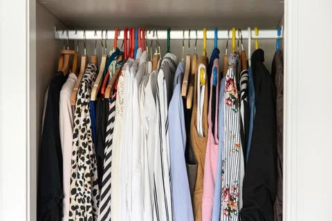 Organized wardrobe with patterned shirts and jackets on hangers, bedroom closet Stock Photos