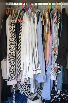 Organized wardrobe with patterned shirts and jackets on hangers, bedroom closet Stock Photos