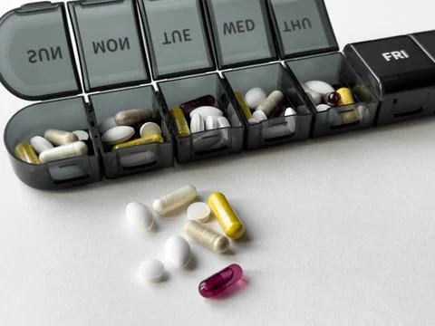 Organized weekly pill box with assorted medications and supplements Foto stock