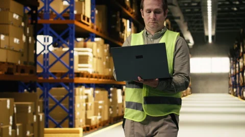 Organizing cargo parcel, man worker with laptop, in distribution center facility Stock Footage 332908425