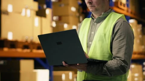 Organizing cargo parcel, man worker with laptop, in distribution center facility Stock Footage 332910674