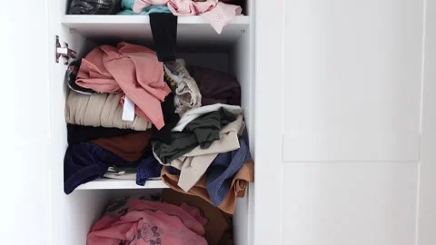 Organizing a closet space with neatly folded and stacked clothes 動画素材 305894560
