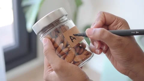 Organizing a jar of almonds with a label for easy access Stock Footage 345387932
