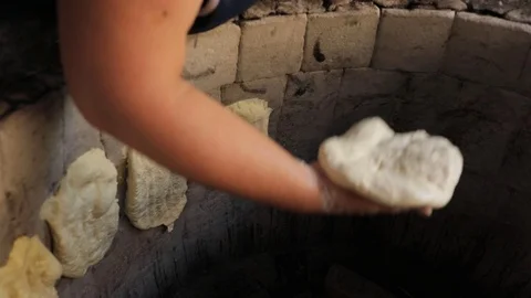 Oriental bread is cooked in tandoor. Closeup the dough on the walls of the oven Stock Footage 123356875