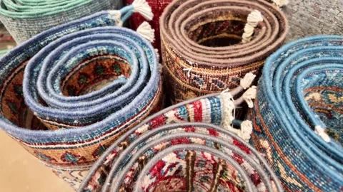 Oriental hand knotted wool rugs displayed in rolls showing intricate patter.. Stock Footage 332897699