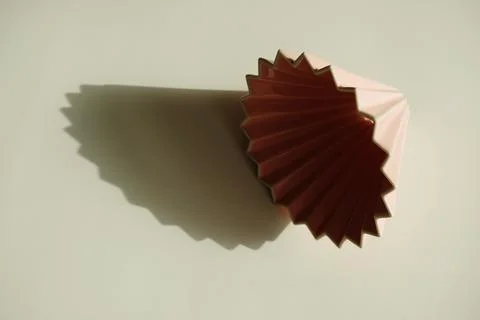 Origami coffee dripper on white background. Bright sunlight and distinct geom Stock Photos