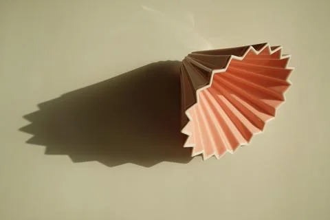 Origami coffee dripper on white background. Bright sunlight and distinct geom Stock Photos