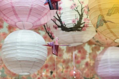 Origami crane hanging from a string, surrounded by spherical lanterns in so.. Stock Photos