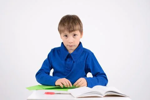 Origami: a studious boy learns in the book to make crafts out of paper Stock Photos