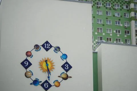 Original clock with an astronomical dial on the building. A school with an Stock Photos