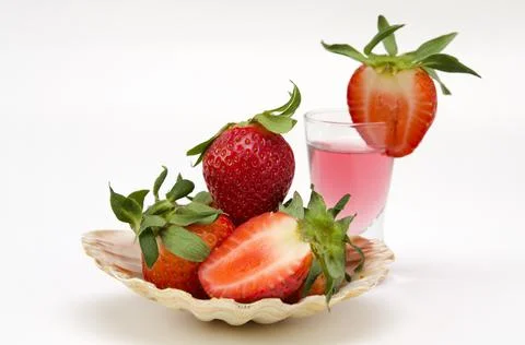 Original serving of strawberries in a shell and a drink with berries on a whi Stock Photos