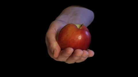 Original sin interpretation with apple in hand on black background Stock Footage 73133492
