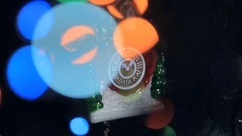 An ornament for a Christmas tree in the form of a clock and a glare of a garland Stock Footage 81903367