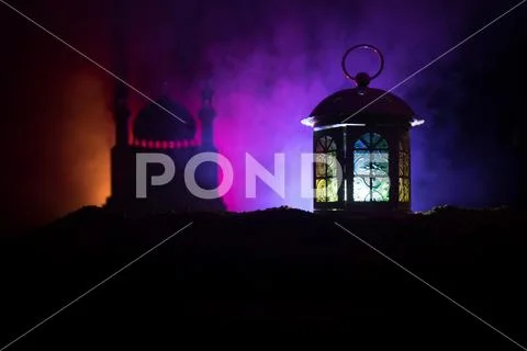 Ornamental Arabic lantern with burning candle glowing at night on dark toned Stock Photos