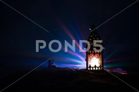 Ornamental Arabic lantern with burning candle glowing at night. Festive greet Stock Photos