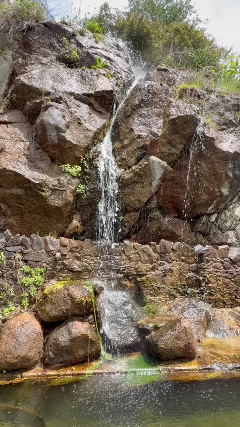 Ornamental water cascade falls over rocky garden formation in peaceful outdoor Video stock 334683063