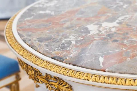 Ornate antique round table featuring a veined marble top, backdrop Stock Photos