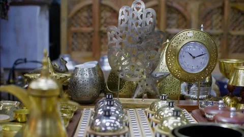 Ornate brass clock among Islamic decorative objects on display table Stock Footage 344996107