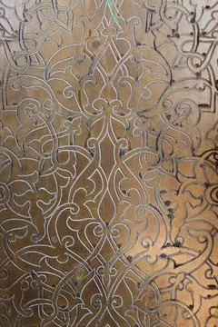 Ornate brass panel featuring engraved Islamic arabesque floral motifs Stock Photos