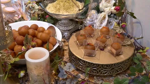 Ornate dessert display featuring Gulab Jamun served in a large white bowl and Stockbeeldmateriaal 335901607