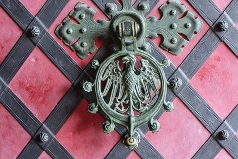 Ornate eagle door knocker on a red and black diamond patterned door Stock Photos