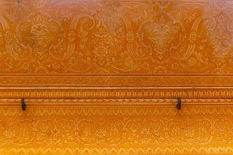 Ornate Floral and Scrollwork Pattern on an Orange-Yellow Palace Wall Stock Photos