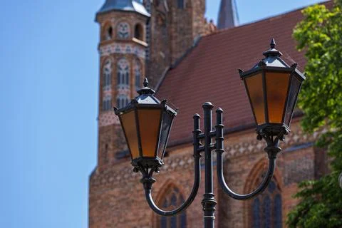 Ornate lantern in front of Medieval Gothic brick architecture in Torun old town Фото