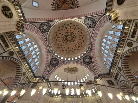 Ornate mosque interior with domed ceiling and hanging lights 库存照片