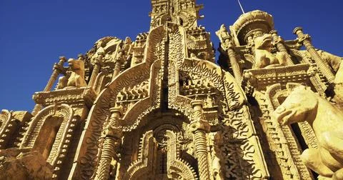 Ornate stone structure adorned with intricate carvings under clear blue sky 库存插图