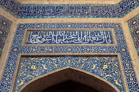 Ornate tilework and Arabic calligraphy above a pointed arch at Kalyan Mosqu.. Stock Photos