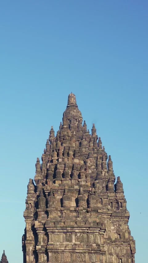 Ornate upper tower of Prambanan Temple rises prominently against a bright c.. Vídeo Stock 341544623