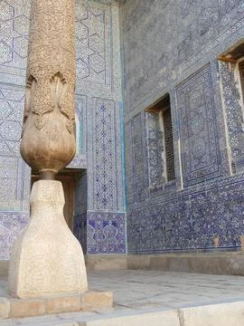 Ornate wood column with patterned base against blue tiled wall, Islamic arc.. Stock Photos