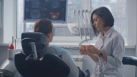 The orthodontist discusses the solution of the patient's problems and the Stock Footage 125618960