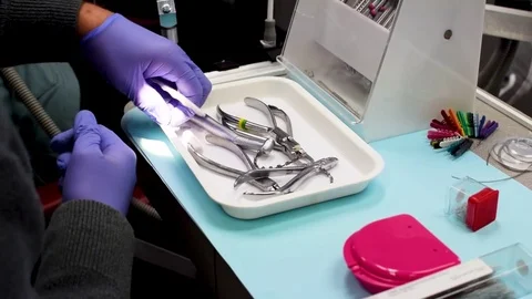 Orthodontist grabbing and using the tools on a table, taking off braces Stock Footage