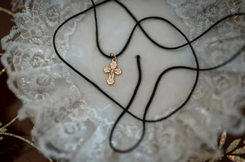 Orthodox cross on a black thread resting on a ceremonial napkin, symbolizing  Stock Photos