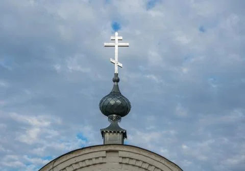 Orthodox cross on the small dome on the background of cloudy sky. Stock Photos