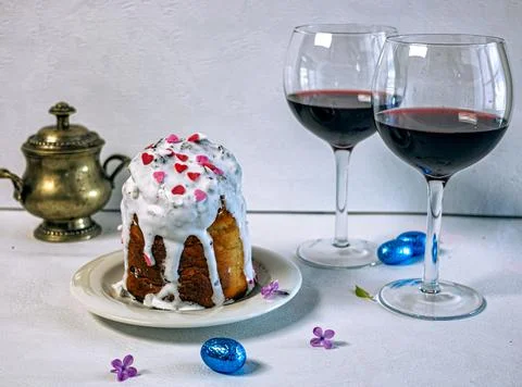 Orthodox Easter cake with white icing and two glasses of red wine. 库存照片
