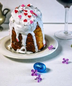 Orthodox Easter cake with white icing and two glasses of red wine. 库存照片
