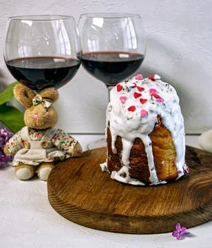 Orthodox Easter cake with white icing and two glasses of red wine. 库存照片