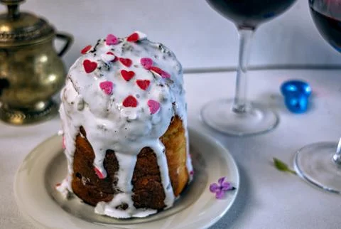 Orthodox Easter cake with white icing and two glasses of red wine. 库存照片