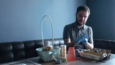 An Orthodox man puts on gloves to paint eggs for Easter Stock Footage 274438314
