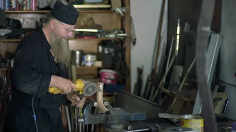 Orthodox monk grinding metal with an angle grinder in his workshop Stock Footage 330188904