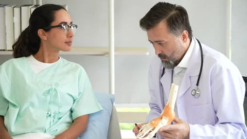 Orthopedic doctor explaining to patient with model of ankle and foot bones .. Stock Footage 278355939