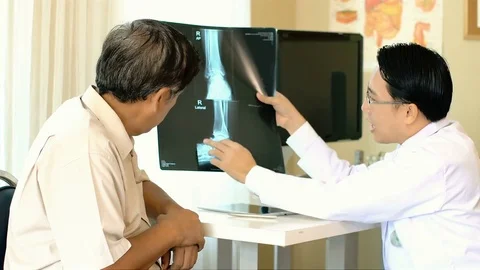 Orthopedist checking x-ray and gives a diagnosis of the patient Stock Footage 83018985