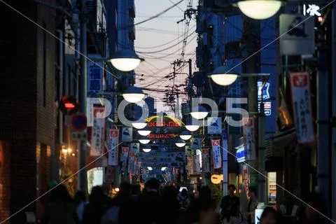 Osaka, Japan - February 2, 2018: Crowd moves down walking street at sunset in Stock Photos