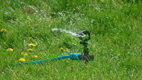 Oscillating smart sprinkler distributing water over fresh grass field Vídeo Stock 337418235