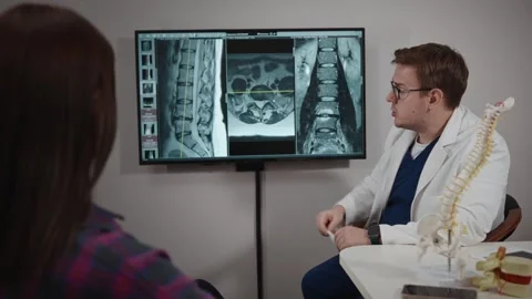An osteopath makes a diagnosis using an MRI image. A man prescribes therapy for Stock Footage 274705162