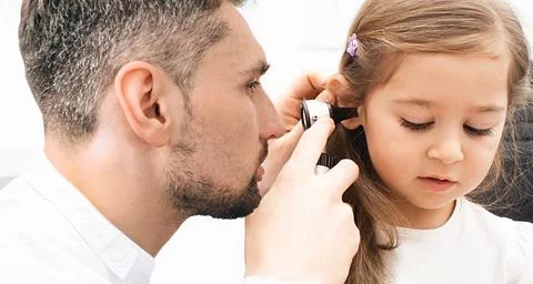 Otolaryngologist checking child's ear using otoscope. Hearing exam for little Stockfoto's