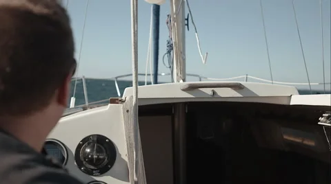 OTS of man piloting a sailboat Stock Footage 48865672