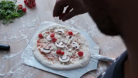 An OTS shot of a man spreading tomatoes on a pizza Video stock 158820863